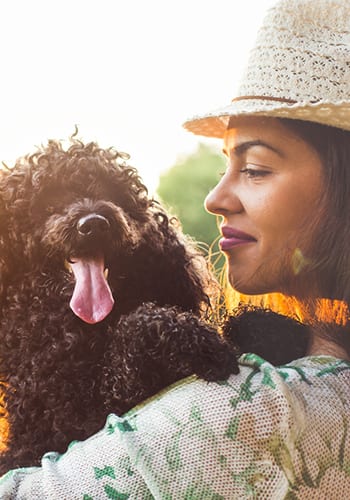 Woman holding her black poodle